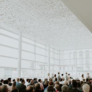 wide view of the Madison Room during a wedding ceremony, highlighting the floor to ceiling windows and white ceilings