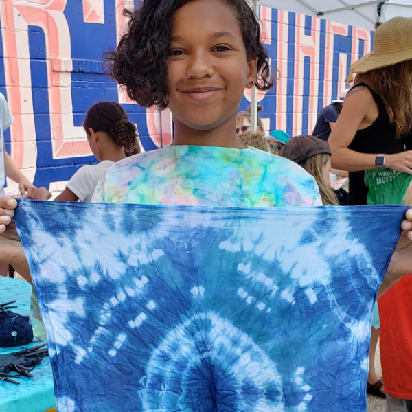 Young kid holding cloth dyed with indigo dye during an Arts in the Alley event