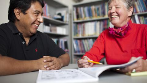 an adult tutoring another adult in a library